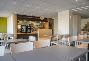a dining room with tables and white chairs at B&B HOTEL Nîmes Ville Active 3 étoiles in Nîmes +25 photos