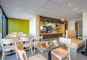 a restaurant with a table and chairs with food on it at B&B HOTEL Nîmes Ville Active 3 étoiles in Nîmes
