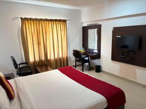 a hotel room with a bed and a desk and a television at JB Residency By Rio Grande in Tiruchirappalli