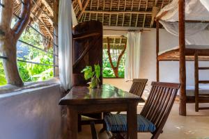 a table and chairs in a room with a bedroom at Distant Relatives Ecolodge & Backpackers in Kilifi