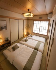 two beds in a room with two windows at 湖畔の詩 BBqが楽しめる隠れ家 琵琶湖徒歩5分 in Takashima
