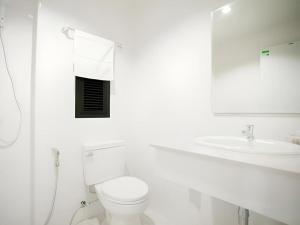 a white bathroom with a toilet and a sink at The Viewpoint Hotel in Ban Wat Tha Maprang