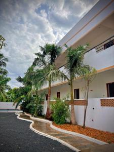 a building with palm trees in front of it at Serenity beach side in Pondicherry