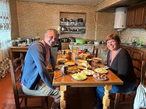 a man and woman sitting at a table with food at Guesthouse Lika in Ushguli