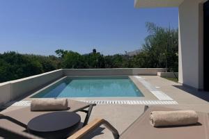 a swimming pool with two chairs and a table at Mirena Exclusive Apartments in Afantou