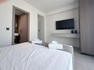 a white bedroom with a bed with towels on it at Mirena Exclusive Apartments in Afantou +29 photos