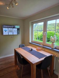 a conference room with a wooden table and two windows at Ferienwohnung Talblick in Schmallenberg