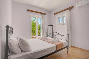 a bedroom with a bed with white sheets and a window at Alkioni Sea View Apartment in Kato Zakros