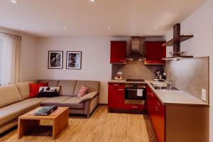 a living room with a couch and a kitchen with red cabinets at Schiebenrothenhof in Simonswald