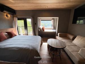 a bedroom with a bed and a table and a couch at Retreat Hotel ENTO ISESHIMA in Funakoshi