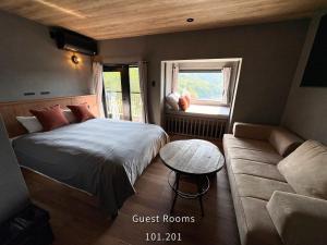 a bedroom with a bed and a couch and a window at Retreat Hotel ENTO ISESHIMA in Funakoshi