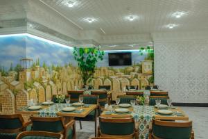 a dining room with tables and chairs and a large mural at Aida hotel PREMIUM in Bukhara