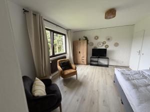 a bedroom with a bed and two chairs and a television at Gemütliche Ferienwohnung direkt am Waldrand in Dörentrup