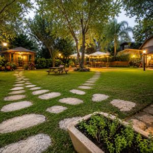 a walkway in a park at night with a picnic table at שורשי הגליל - 6 בקתות מדהימות עם ג'קוזי, גינה וקרבה לנחלים in Yuval