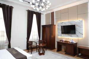 a hotel room with a bed and a desk and a tv at Boulevard Palace Hotel in Samarkand