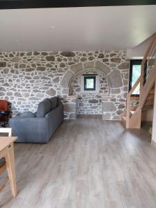 a living room with a couch and a stone wall at Gîte Le Valeix in Neuvic