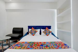 a bedroom with a bed and a chair at FabHotel MV Luxury Rooms in Hyderabad