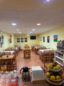 ein Speisesaal mit Tischen und Stühlen und eine Cafeteria in der Unterkunft Hotel La Guindal in Les Arriondes