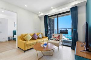 a living room with a yellow couch and a table at Skyline Hillside Apartment Phu Quoc in Phú Quốc