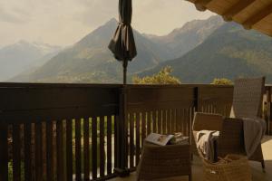 a balcony with two chairs and an umbrella and mountains at Landpalais Goyenhof - Deluxe Suites & Breakfast in Schenna