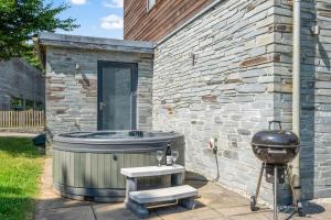 a hot tub and a grill next to a brick building at House 8 in Looe