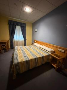 ein Schlafzimmer mit einem großen Bett und einem Fenster in der Unterkunft Hotel La Guindal in Les Arriondes
