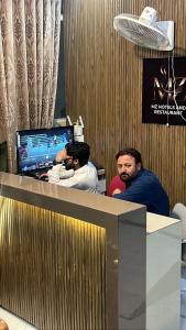 two men sitting at a desk with a computer at Abu Khalid By MZ Hotels & Restaurant in Mingāora