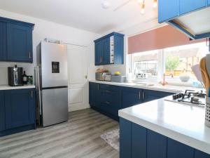 a kitchen with blue cabinets and a stainless steel refrigerator at 6 Niddrie Marischal Road in Edinburgh