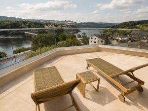 eine Terrasse mit zwei Stühlen und einer Bank auf einem Dach in der Unterkunft Hotel Henko in Portomarin