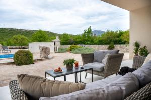 a patio with a couch and chairs and a table at Wellnes Villa Silentio With Pool in Duge Njive