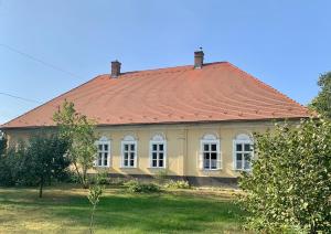 a yellow house with a red roof at Dinnyés Kúria Dabas in Dabas +8 photos
