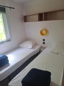 two beds in a small room with a window at Le Village des Pingouins à Porspoder in Porspoder