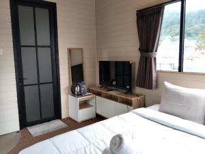 a bedroom with a bed and a tv and a window at Beji Bedugul Glamping in Bedugul