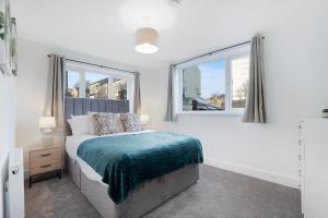 a white bedroom with a bed and two windows at NEW! Spacious 4BR in Sidney in Bishop Auckland