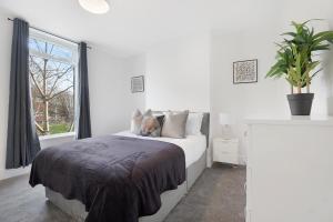 a white bedroom with a bed and a window at NEW! Spacious 4BR in Sidney in Bishop Auckland