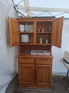 a wooden cabinet with plates and dishes in it at Le Village des Pingouins à Porspoder in Porspoder