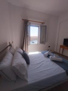 a large white bed with pillows and a window at Faros House Kythnos in Loutra