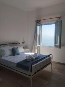 a bedroom with a bed with two pillows and a window at Faros House Kythnos in Loutra