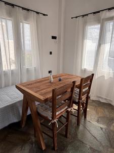 a wooden table and chairs in a room with windows at Faros House Kythnos in Loutra +21 photos