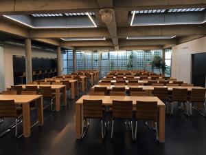 an empty lecture hall with tables and chairs at Geneva Hostel in Geneva