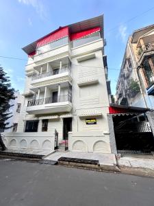 a white building with red accents on a street at Hotel Fivetel in kolkata