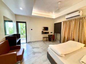 a bedroom with a bed and a chair and a desk at Hotel Fivetel in kolkata