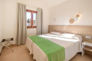 a bedroom with a large white bed with a green blanket at Cabot Club Torreblanca in Sa Coma +94 photos