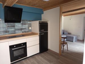 a kitchen with a black refrigerator and a living room at As Casiñas da Mina in Fechas
