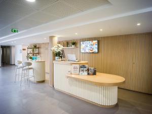 a waiting room with a counter and a table at BRIT HOTEL CONFORT Roissy Saint-Witz in Saint-Witz