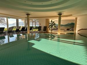 a swimming pool in a house with chairs and water at Werzers Hotel Resort Pörtschach in Pörtschach am Wörthersee