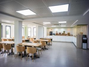 a cafeteria with tables and chairs and a kitchen at BRIT HOTEL CONFORT Roissy Saint-Witz in Saint-Witz +47 photos