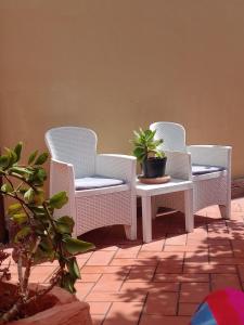 three wicker chairs and a table with a potted plant at Appartamento con giardino e posto auto privato in Follonica