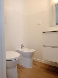 a white bathroom with a toilet and a sink at Appartamento con giardino e posto auto privato in Follonica +9 photos