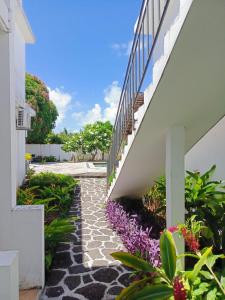 a walkway next to a white building with flowers at Résidences Le Beau Manguier in Pereybere
